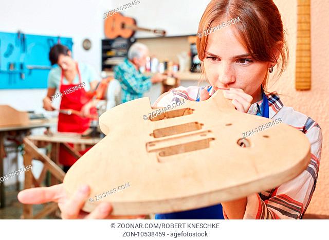 Junge Frau als Gitarrenbauer Lehrling fertigt eine neue Gitarre an