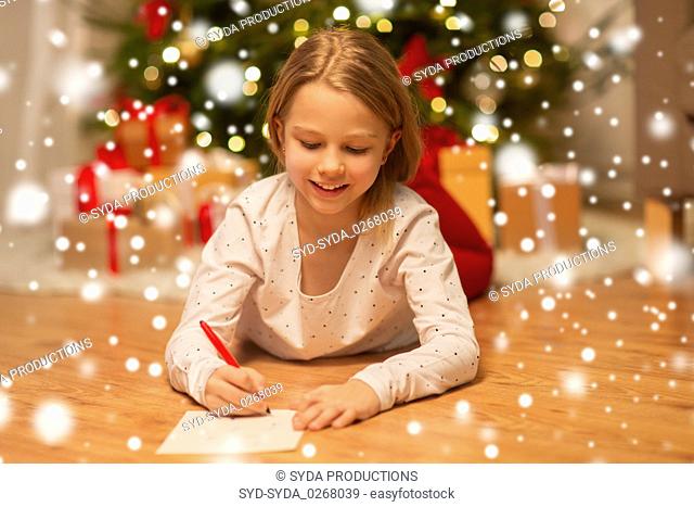 smiling girl writing christmas wish list at home