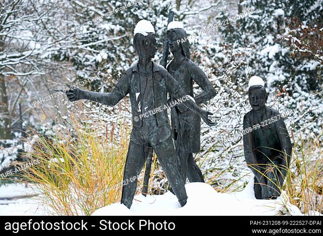 06 December 2023, Hamburg: Snow lies in Jacobipark on the group of figures ""Latsch-in"" (bronze 1996) designed by Theophil Steinbrenner