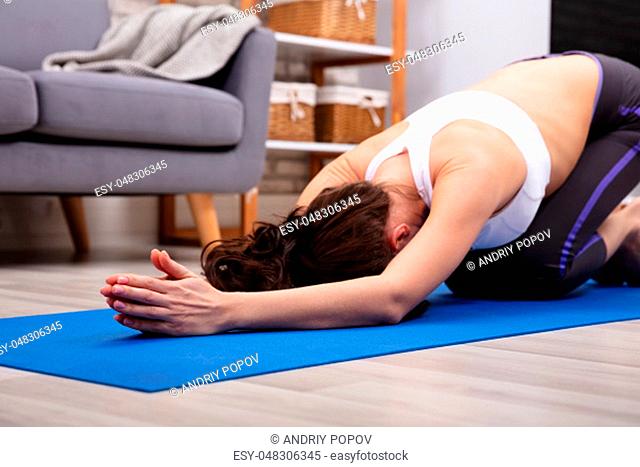 Athletic Woman Doing Yoga On Blue Fitness Mat At Home