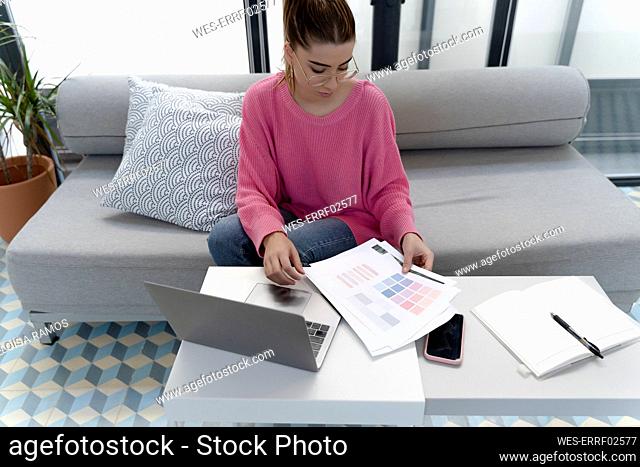 Young woman sitting on the couch looking at printouts