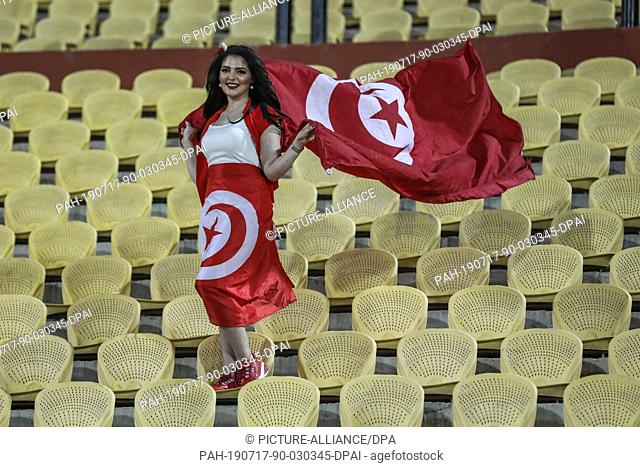 17 July 2019, Egypt, Cairo: A woman waves the Tunisian nation flag ahead of the 2019 Africa Cup of Nations third place final soccer match between Tunisia and...