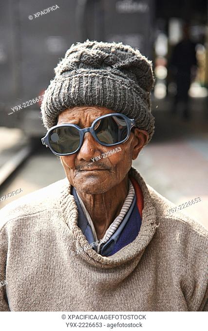 An old man with trendy sunglasses and a beanie collecting scavenging for coal