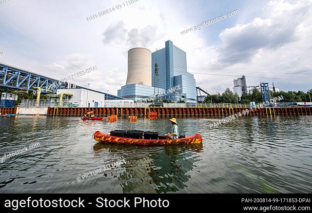 14 August 2020, North Rhine-Westphalia, Datteln: A climate activist paddles his canoe, which is symbolically loaded with coal from Colombia and Russia