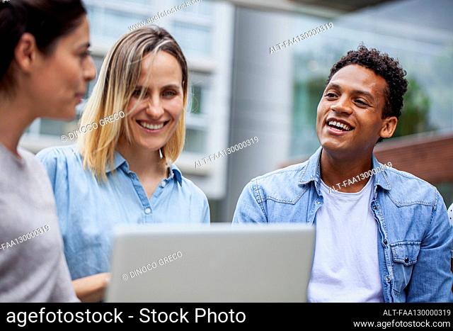 Coworkers sitting outdoors during informal meeting