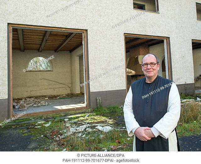 11 November 2019, Brandenburg, Treppeln: Cistercian monk Father Simeon Wester stands in front of the building of the abandoned Treppeln Forester's Lodge
