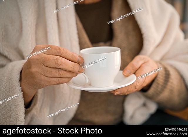 Woman Wearing Grey Cardigan And Wrapped In A Woolen Plaid Holding A White Cup With Tea. Close-up Shot