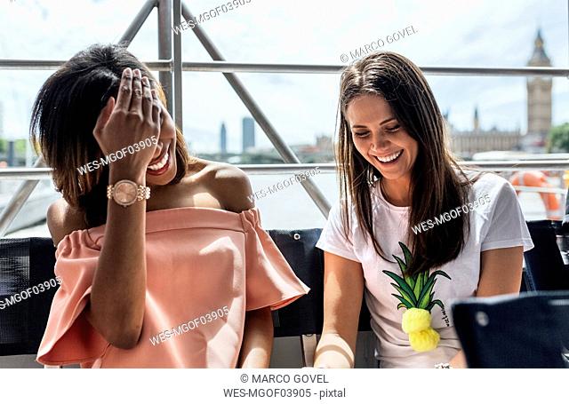 UK, London, two happy women traveling by boat on the River Thames