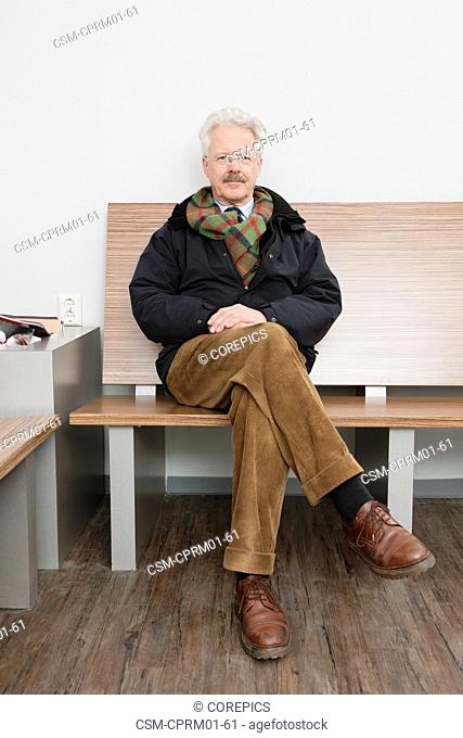 elderly man, sitting patiently in the waiting room of a medical practice, waiting for his turn