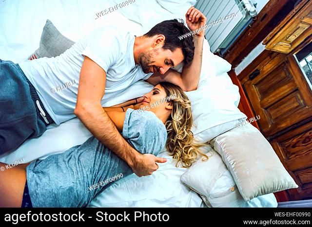 Affectionate young couple cuddling in bed at home