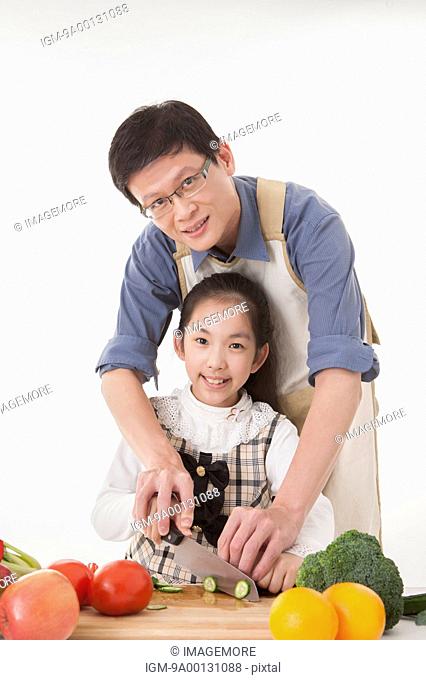 Father teaching daughter to cut vegetables