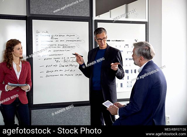 Two businessmen and businesswoman working together on a project in office