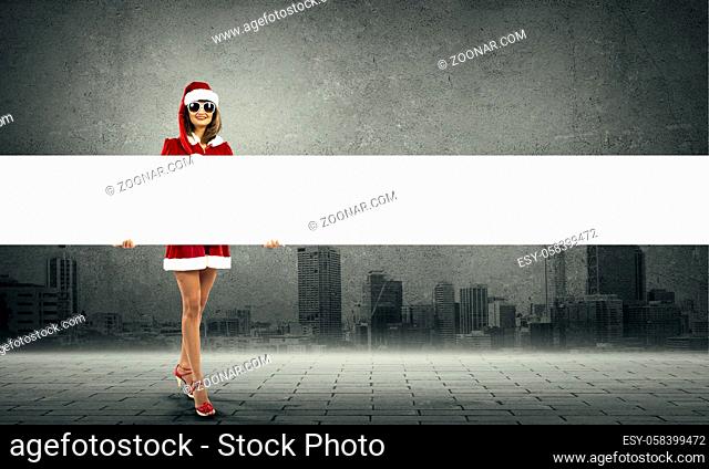 Full length of Christmas Santa girl holding white blank banner