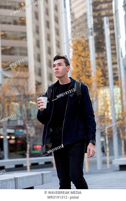 Man walking on street while having coffee