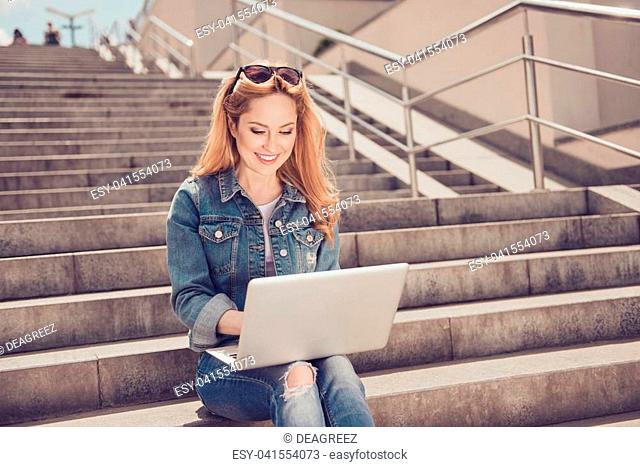 People lifestyle leisure concept. Portrait of cheerful relaxed inspiring beautiful woman casual stylish jacket holding netbook on knees sitting on stone street...