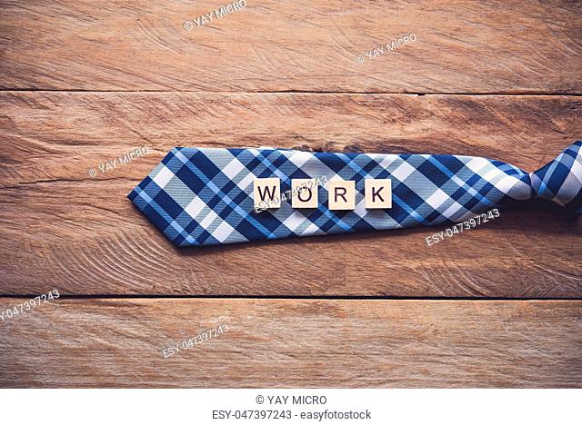 Necktie and the message ""work"" put on wooden floor - Concept of lifestyle for businessman