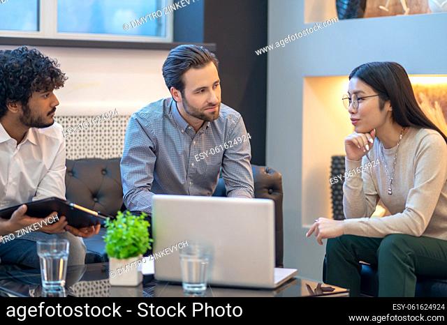 Female employee and her two male coworkers holding the meeting in a cozy company office