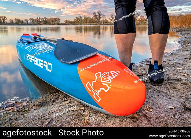 Fort Collins, CO, USA - October 17, 2018: Male paddler with a racing stand up paddleboard on calm lake in fall scenery in northern Colorado - 2016 All Star race...