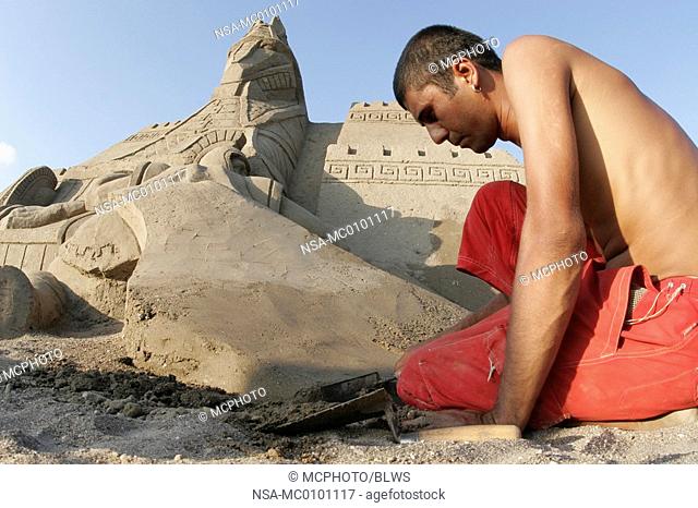 artist building sand sculpture trojan war at the sand city festival at Lara Beach