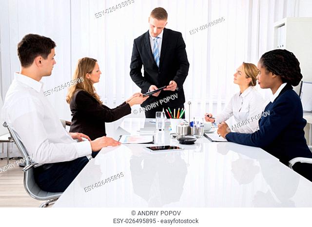 Female Colleague Showing Document To Young Businessman In Meeting