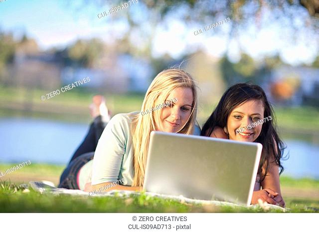 Two young women in park looking at laptop