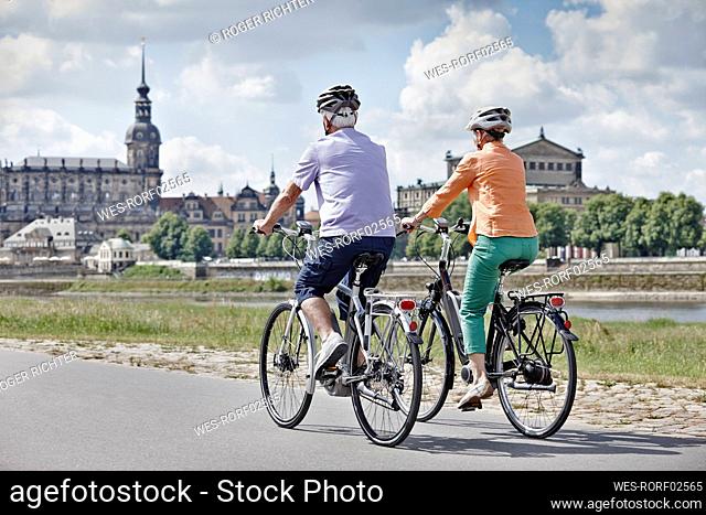 Tourist couple riding electric bicycle at Semper Opera House, Dresden, Germany