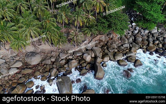 Aerial top view of sea waves hitting rocks on the beach in Phuket, Thailand