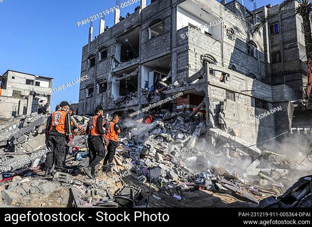 19 December 2023, Palestinian Territories, Rafah: Members of the civil defence teams carry out search and rescue operations in the rubble of a residential...