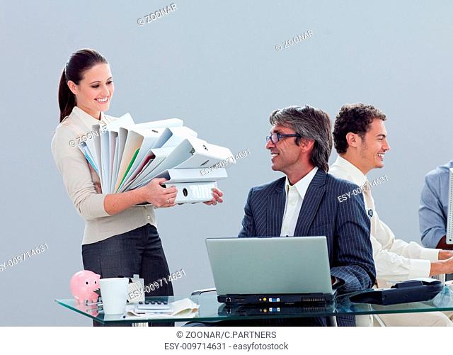 Pretty businesswoman carrying a stack of folders with her colleague