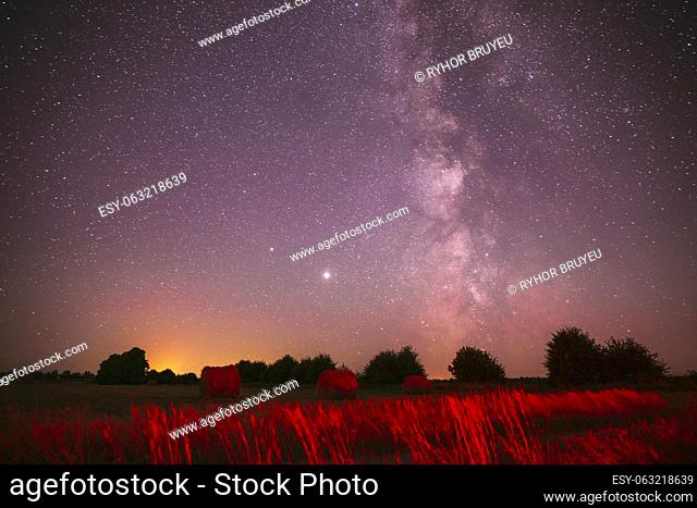 Agricultural Colorful Background Copy Space. Natural Real Night Sky Stars With Milky Way Over Field Meadow With Rolls Of Straw In Fields After Harvest