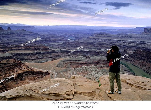 Tourist taking pictures high above the Colorado River from Dead Horse Point, Dead Horse Point State Park, Utah, USA