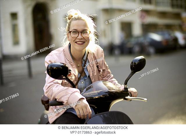 Laughing woman on motor scooter, in Berlin, Germany