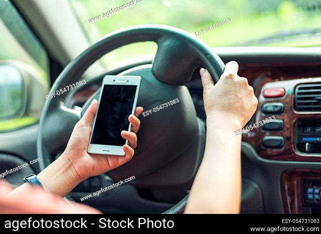 women driver with a cell phone in hand while driving