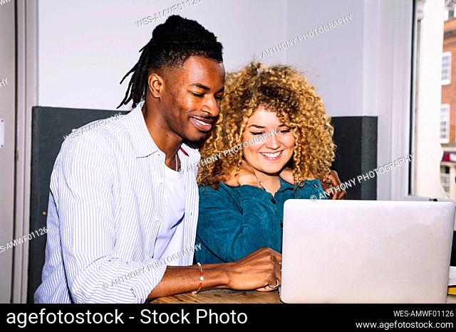 Happy businessman sharing laptop with colleague in office