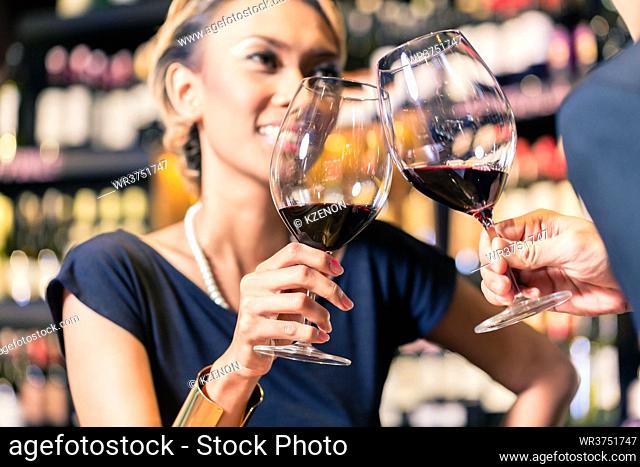 Close up of Asian couple clinking glasses in wine shop