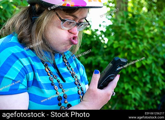 Portrait of a 39 year old white woman with the Down Syndrome, having a video call with her family outdoors, Tienen, Belgium