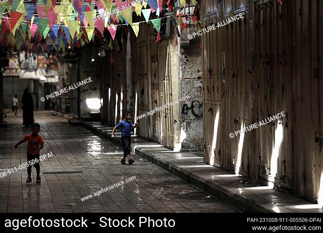 08 October 2023, Palestinian Territories, Nablus: Children play in front of closed shops during a general strike. Palestinian national and Islamic groups...