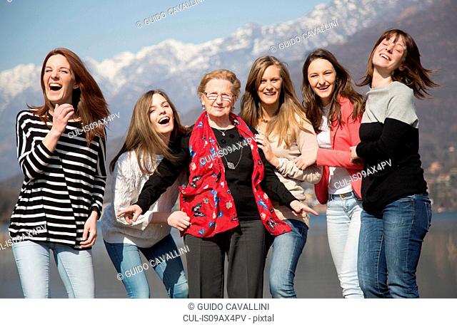 Grandmother with granddaughters in front of snow capped mountains looking at camera smiling