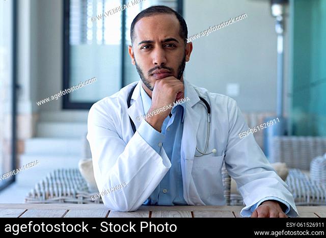 Portrait of caucasian male doctor looking at the camera and rubbing his chin