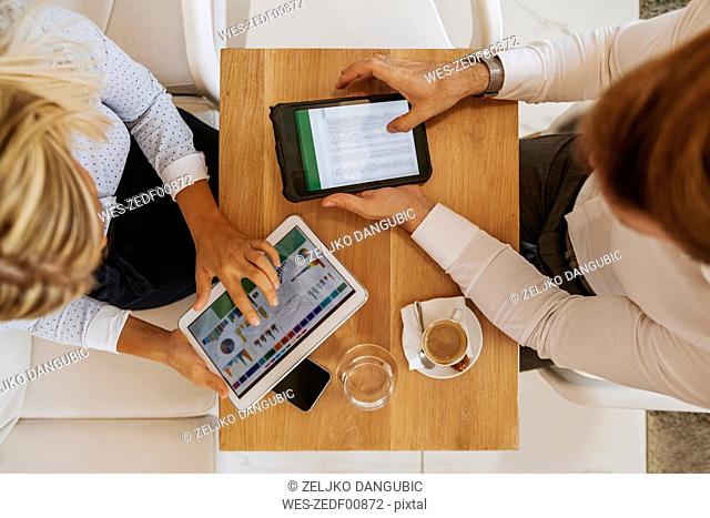 Businessman and businesswoman using tablets in a cafe