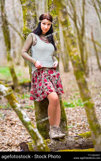 Country-girl is standing inclined on a tree in a Autumnal forest