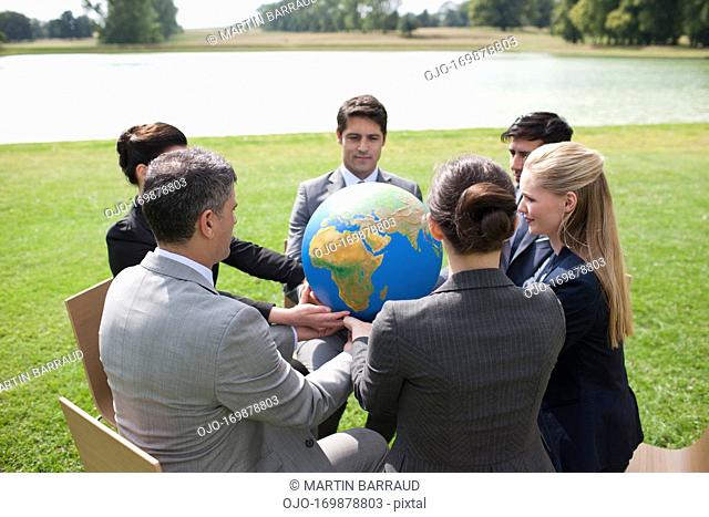 Business people having meeting outdoors looking at globe