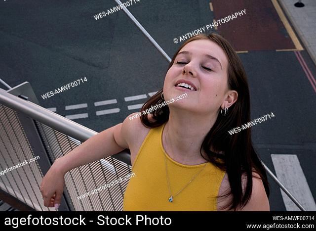Young woman with eyes closed leaning on railing