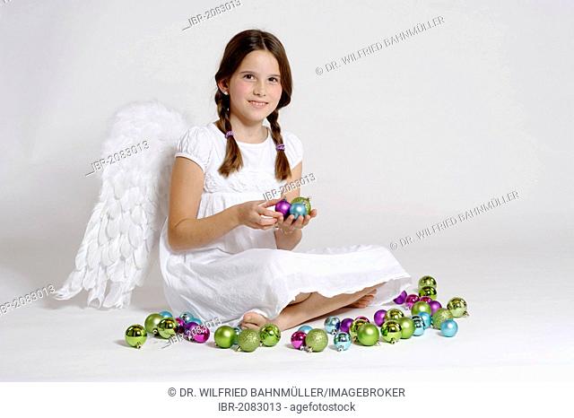 Girl dressed up as Christmas angel, Christ Child with Christmas baubles