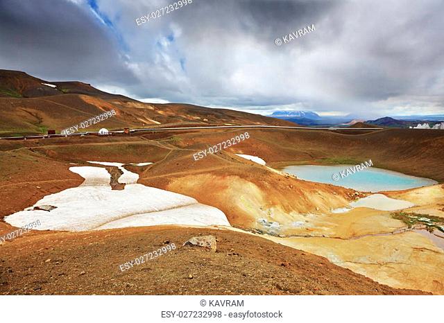 July in Iceland. Krafla lake in the crater of an extinct volcano. On the banks are last year's snow fields