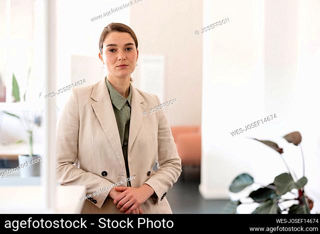 Confident businesswoman with hands clasped in office