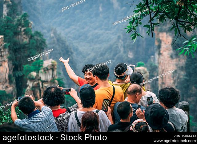 Zhangjiajie, China - August 2019 : Tourists taking selifie pictures on mobile phones on the viewpoint in Tianzi mountain range, Avatar mountains nature park
