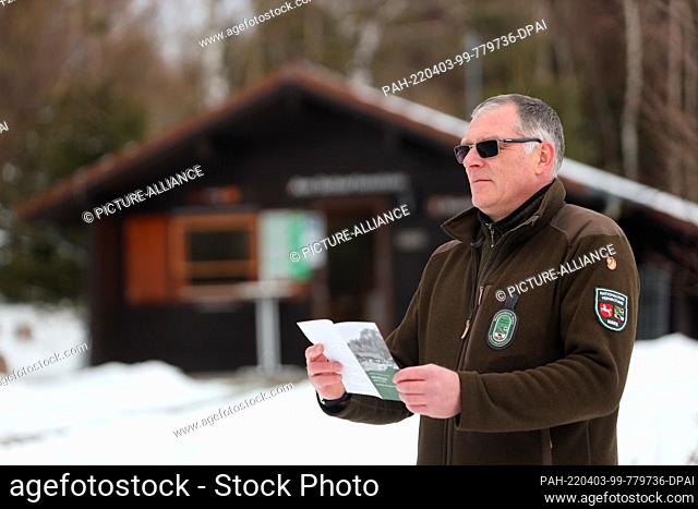 03 April 2022, Saxony-Anhalt, Ilsenburg: National Park Ranger Stephan Sandtner stands with a leaflet in front of the ranger station at Scharfenstein near...