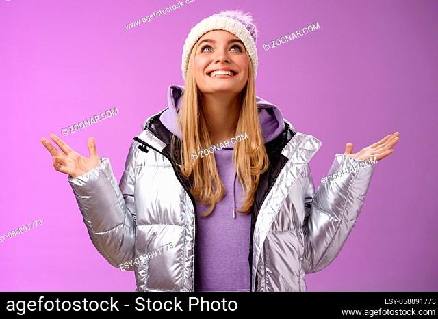 Thankful happy cute attractive blond young 25s woman in winter hat silver trendy jacket raise hands look up grateful god dream come true smiling delighted...