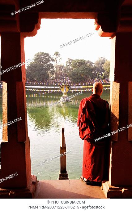 Monk standing at lakeside, Mucalinda Lake, Bodhgaya, Gaya, Bihar, India